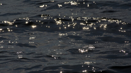 dark blue rippling water surface with ligh reflections background 
