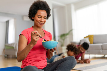 African american woman with family on background eating a healthy salad after workout. Fitness
