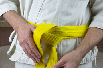 Kyokushinkai artist wears yellow sash on his kimono around his waist, the insignia of martial...