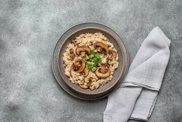 Risotto with mushrooms on a gray grunge background. Italian dish. Top view, flat lay, copy space.