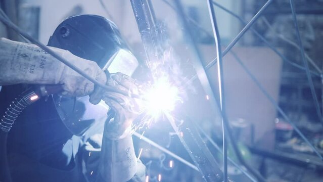 Blacksmith engaged in the welding of a metal art piece.