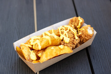 Fast food dish of french fries and chicken in a cardboard container