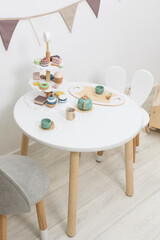 Kids play tea party. Children's table wooden mugs and cakes. Time for tea. Children's eco-friendly wooden toys. Role game for young children. Tea party dolls. Scandinavian minimalist decor childre