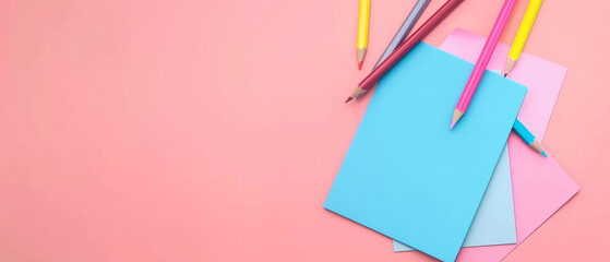 A minimalist composition with colorful stationery on a soft pink background, evoking creativity.