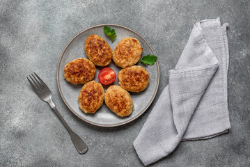 Fried meat cutlets in a plate on a gray concrete background. Top view, flat lay.