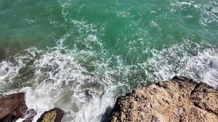 Turquoise ocean waves crashing against rugged rocks, perfect for summer travel themes and World Oceans Day environmental awareness campaigns