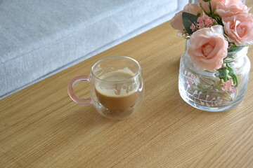 Kawa w ozdobnej szklance na blacie stolika drewnianego 