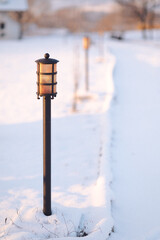 a street light covered in snow next to a road sign