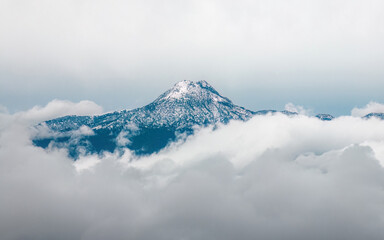 Fototapeta premium Scenic view of the majestic mountain hidden in the sea of clouds. Nevado de Colima, Mexico