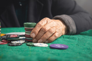 Elderly female hand holding casino games chips.
