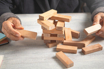 Hand of elderly woman stacking wooden blocks.