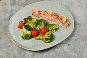 Plate with broccoli, tomatoes, and fish on a white background