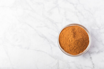 Cinnamon powder in a bowl on a textured wooden background. Spicy spice for baking, desserts and drinks. Fragrant ground cinnamon. Cinnamon stick. Place for text. Copy space.