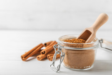 Cinnamon powder in a bowl on a textured wooden background. Spicy spice for baking, desserts and drinks. Fragrant ground cinnamon. Cinnamon stick. Place for text. Copy space.