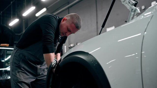 close up At a service station master auto mechanic unscrews bolts on the interior panel of a white car