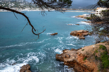 Turquoise sea, rocks, and a small town in Port d'Andratx, Mallorca, Spain.