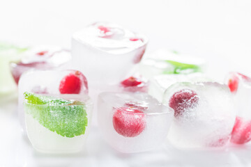 frozen red berries in ice cubes with mint on stone background