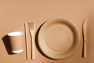 A set of paper utensils and wooden cutlery on a brown background. Eco friendly, zero waste concept....