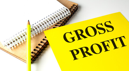 GROSS PROFIT text on yellow paper with notebooks