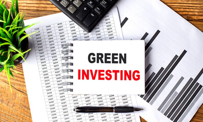 GREEN INVESTING text on notebook on chart with calculator and pen - Powered by Adobe