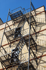 Fire escape hangs from brick buildings facade in city skyline