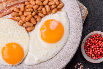 English breakfast with fried eggs, bacon, beans, tomatoes, spices and herbs