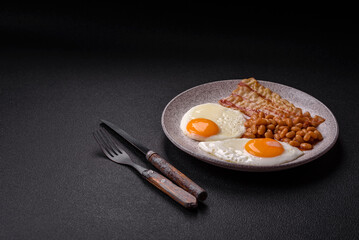 English breakfast with fried eggs, bacon, beans, tomatoes, spices and herbs