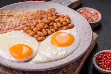 English breakfast with fried eggs, bacon, beans, tomatoes, spices and herbs