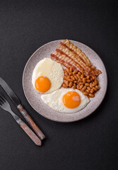 English breakfast with fried eggs, bacon, beans, tomatoes, spices and herbs
