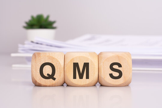 QMS 'Quality Management System' - text on wooden cubes on the gray table. business concept