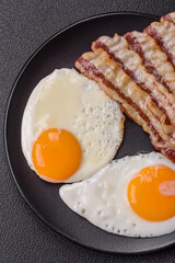 English breakfast with fried eggs, bacon, beans, tomatoes, spices and herbs