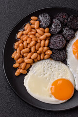 English breakfast with fried eggs, bacon, beans, tomatoes, spices and herbs