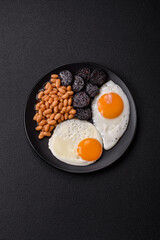 English breakfast with fried eggs, bacon, beans, tomatoes, spices and herbs