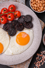 English breakfast with fried eggs, bacon, beans, tomatoes, spices and herbs