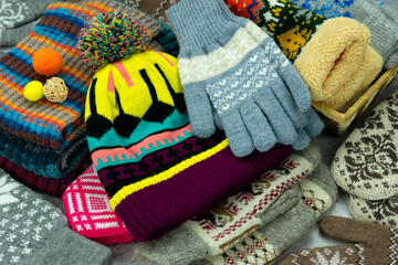 Hats, mittens and gloves are folded together. Lots of warm clothes in the form of hats, mittens and gloves for autumn and winter. Knitted clothing for cold seasons.