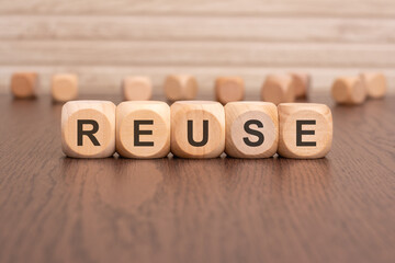 the text 'REUSE' is written on wooden cubes on a brown background