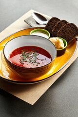 Traditional Ukrainian borscht with rye bread, sour cream, and condiments