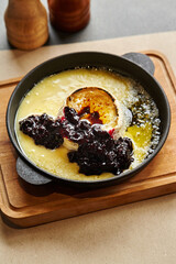 Browned baked Camembert cheese with currant jam in skillet