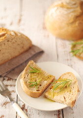 A loaf of rye bread with oil and rosemary in rustic style