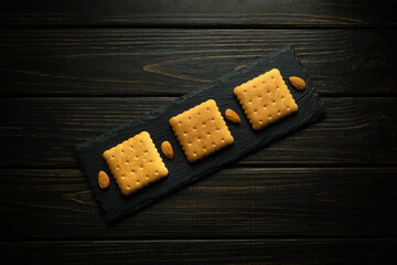 Square cookies on a serving board with almond nuts prepared for dessert. Sweet snack concept on vintage table