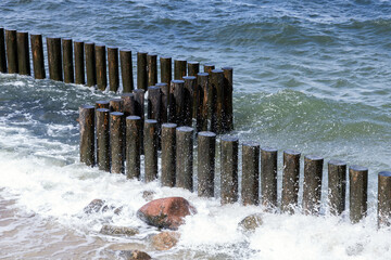 Shore waves and wooden pillars as a part of breakwater structure