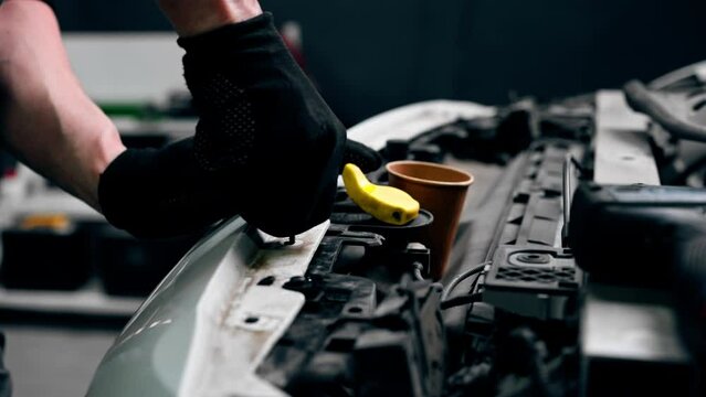 vertical video close up At a service station master auto mechanic unscrews bolts on the interior panel of a white car