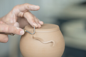 A potter works with a tool on a potter's wheel. Close-up of a man's hands. 