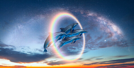 Group of dolphins jumping up from the sea amazing sunset in the background with rounde rainbow and Milky Way galaxy © muratart