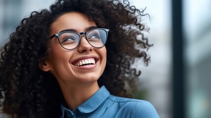 A woman with a joyful expression wears glasses and a blue shirt