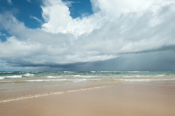 A tropical beach in Brazil with waves and a sky with lots of clouds.