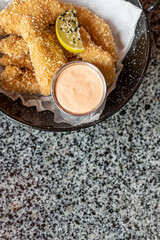 golden deep-fried battered chicken nuggets.succulent chicken chunks ensconced in a delectable batter, crisped up with Panko, and draped in sauce closeup on the plate on the table.
