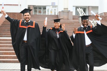 Diverse international students with diplomas attending graduation ceremony, happy multiracial group...