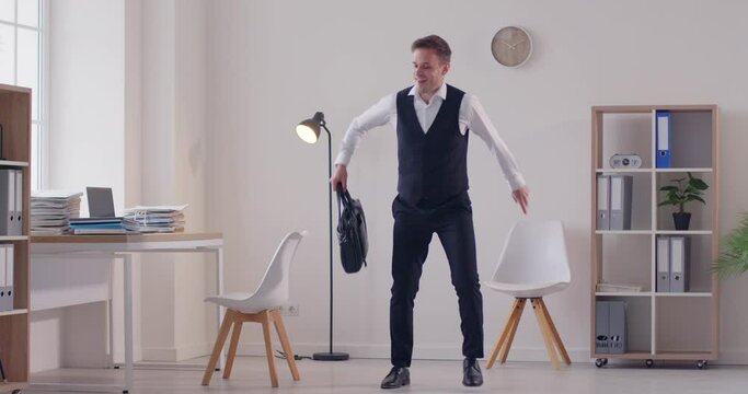 Happy cheerful carefree satisfied man office worker with briefcase celebrating promotion and good paycheck, having fun at end of work day, feeling full of energy, dancing funny TGIF dance and jumping