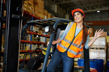 female worker smiling and say hello or goodbye pose to someone beside forklift in warehouse storage